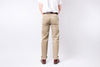 Person wearing beige pants and a white shirt on a plain background
