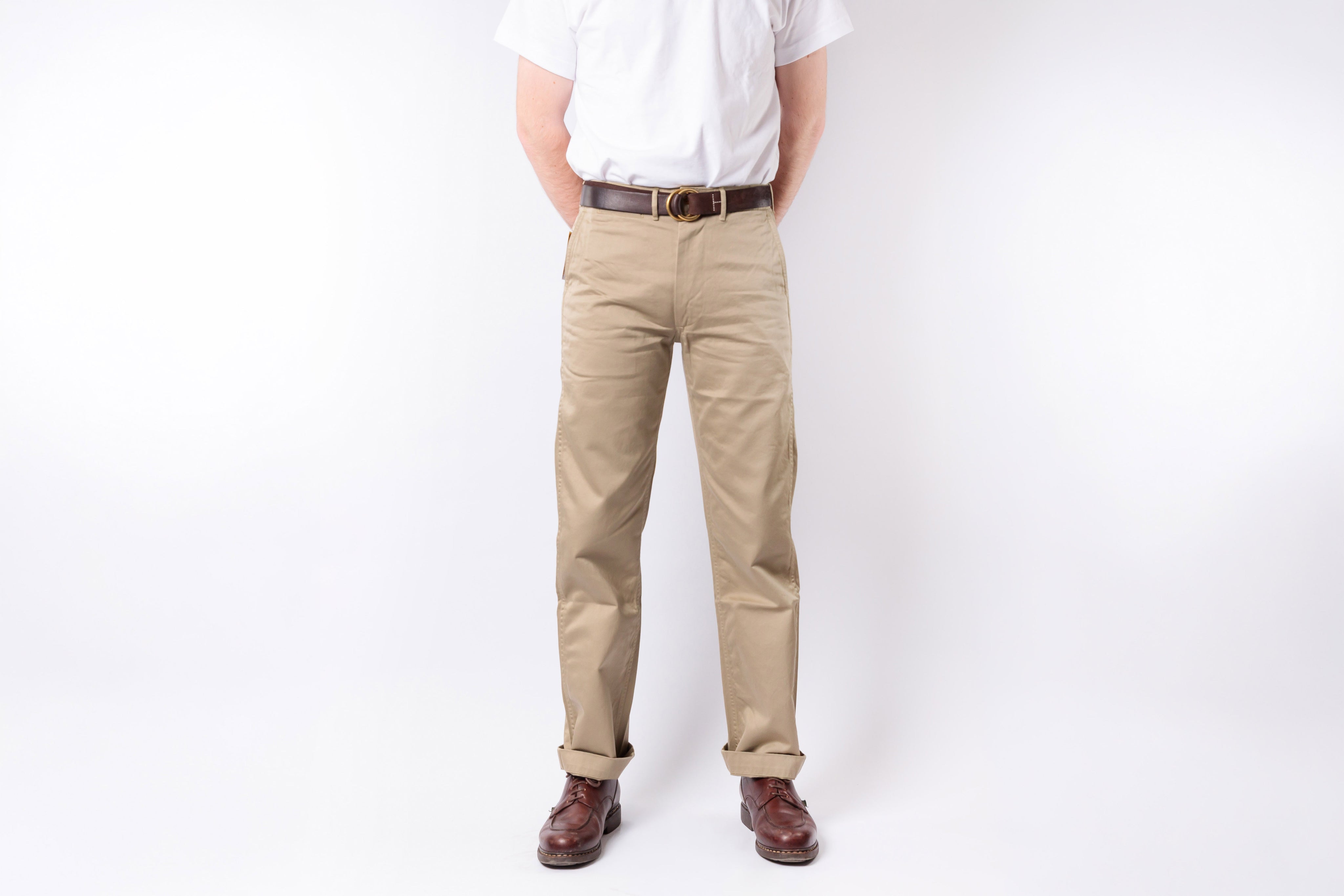 Person wearing beige pants and a white shirt on a white background
