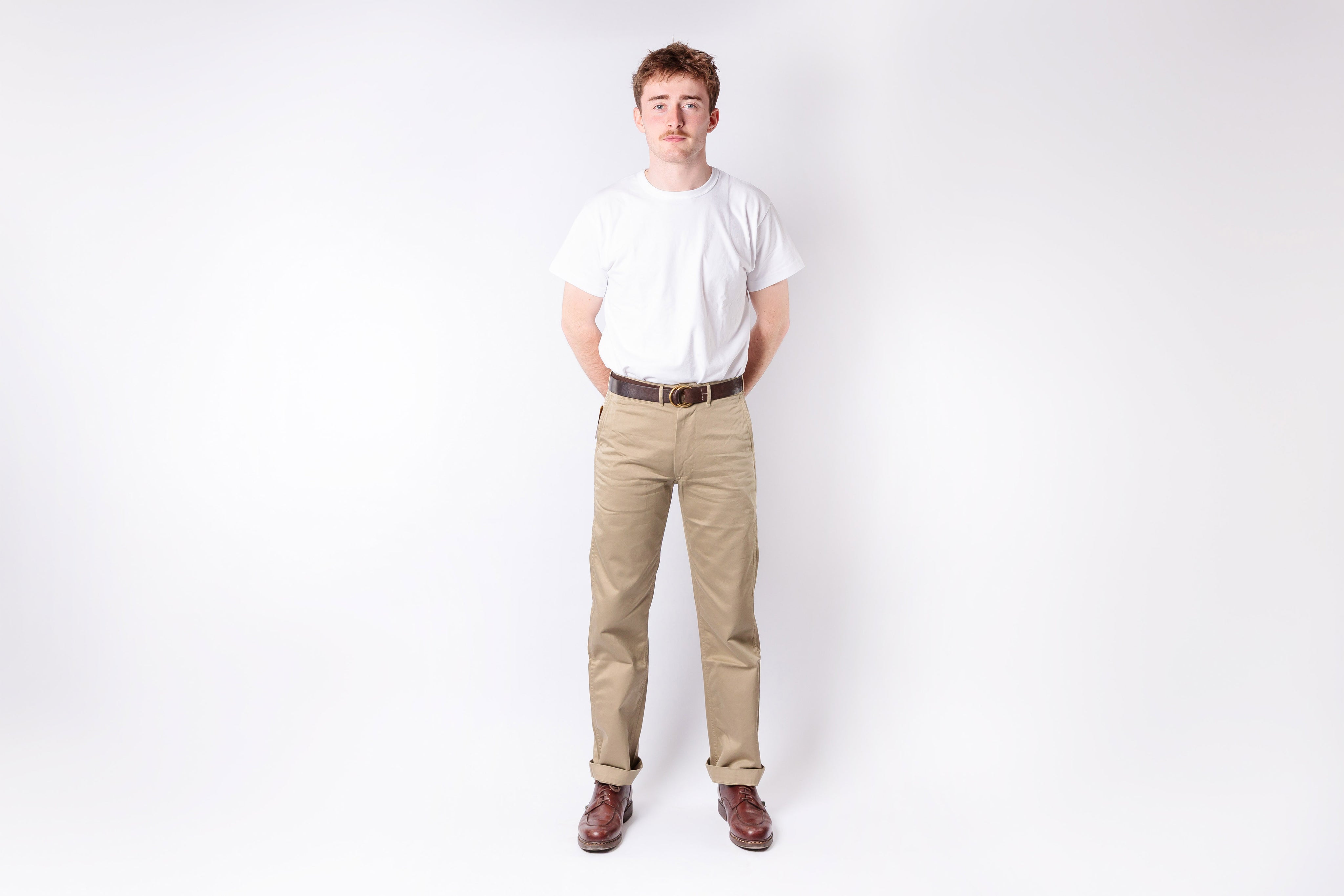 Person wearing a white shirt and beige pants on a white background