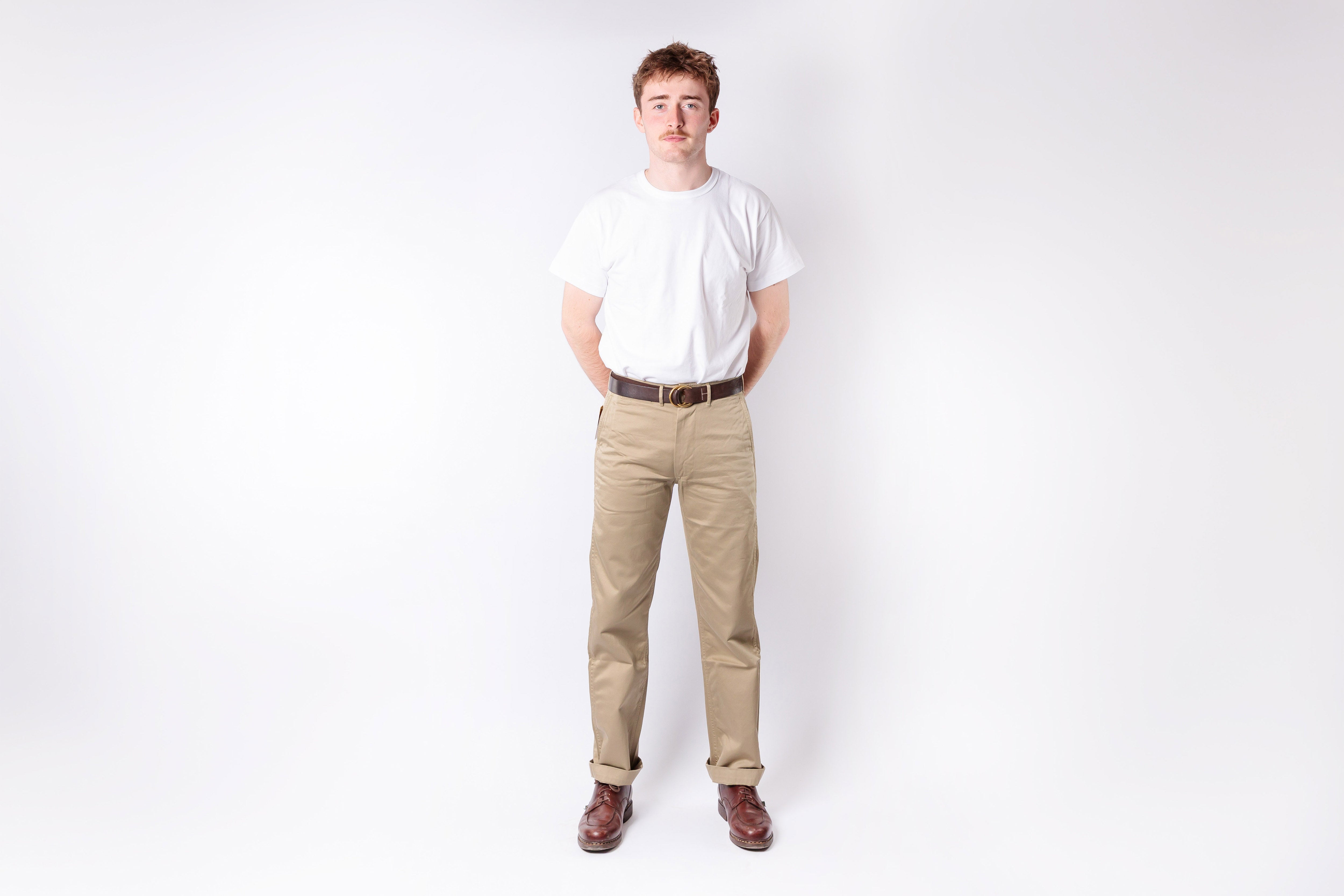 Person wearing a white shirt and beige pants on a white background