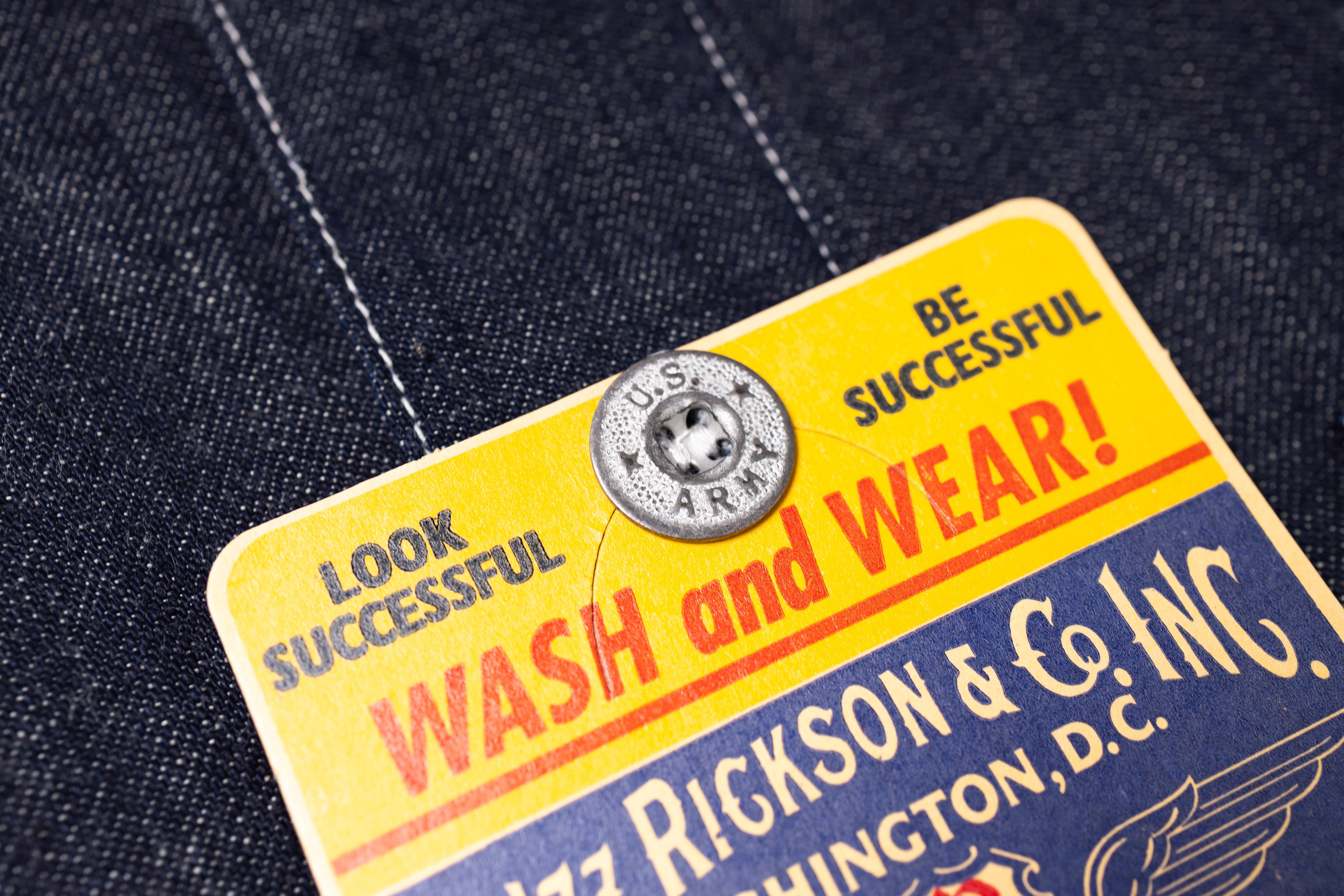 Vintage-style label on denim fabric with text and a button.