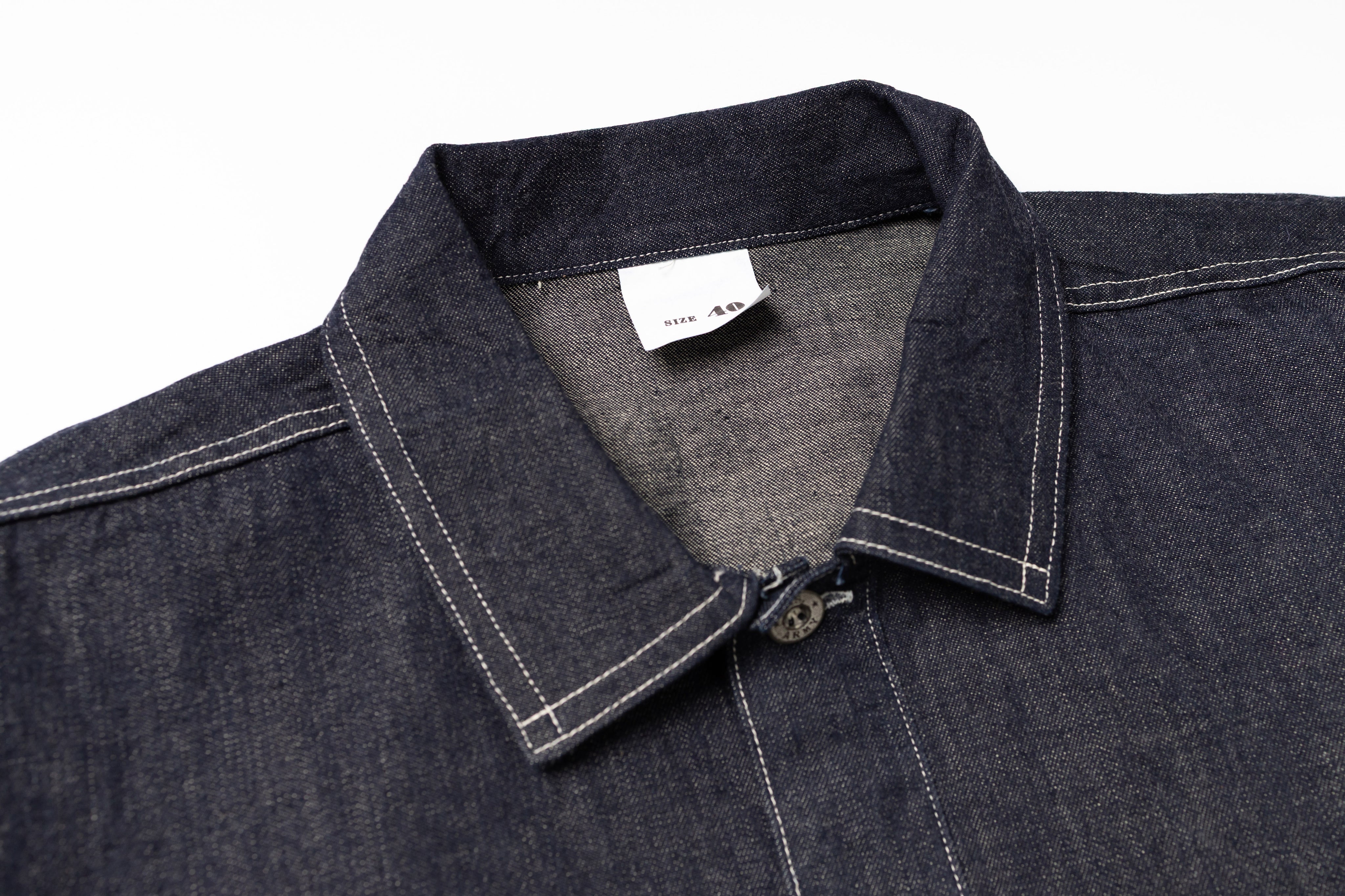 Close-up of a dark denim shirt with collar and label on a white background