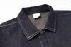 Close-up of a dark denim shirt with collar and label on a white background