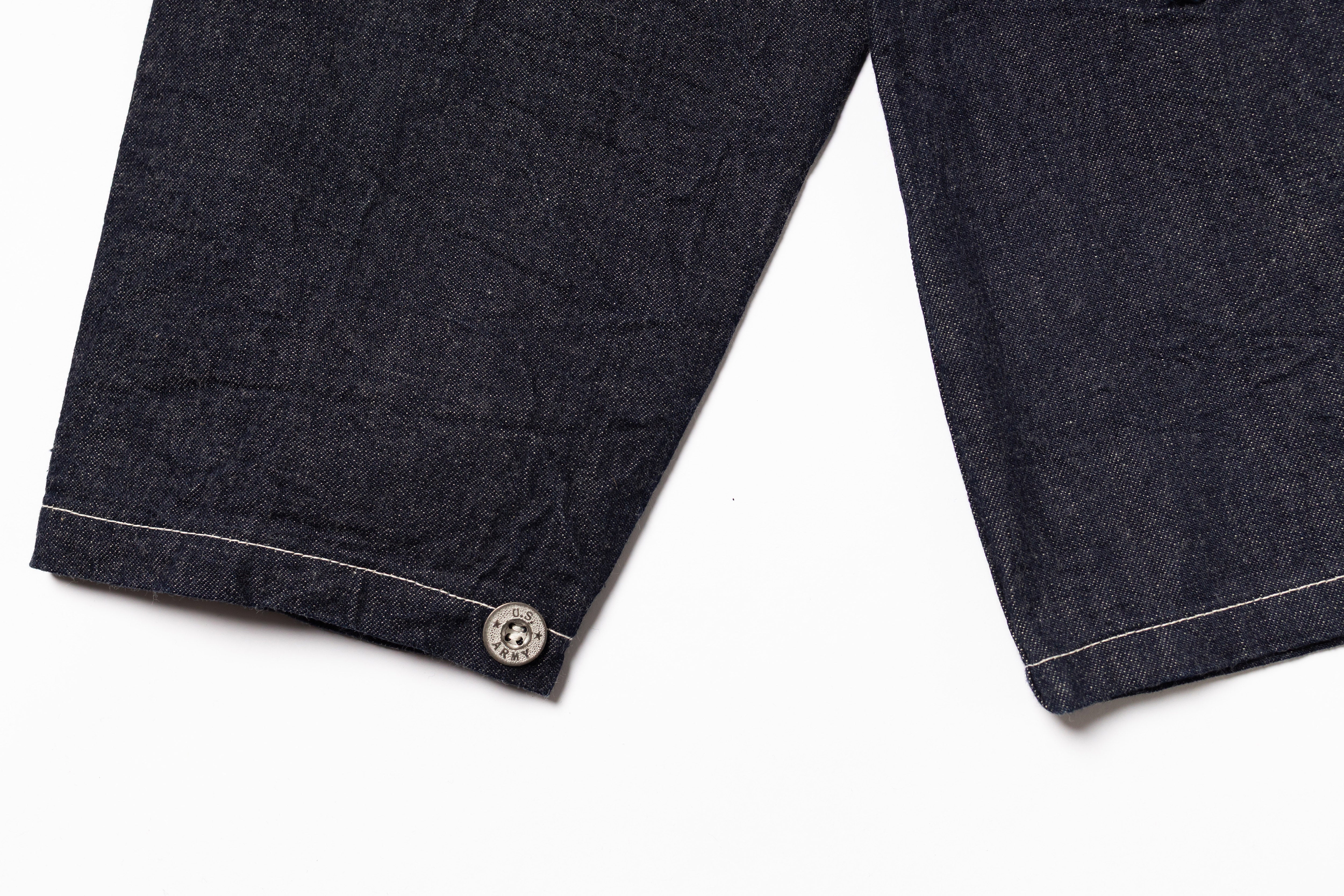 Close-up of dark denim fabric with a button on a white background