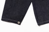 Close-up of dark denim fabric with a button on a white background