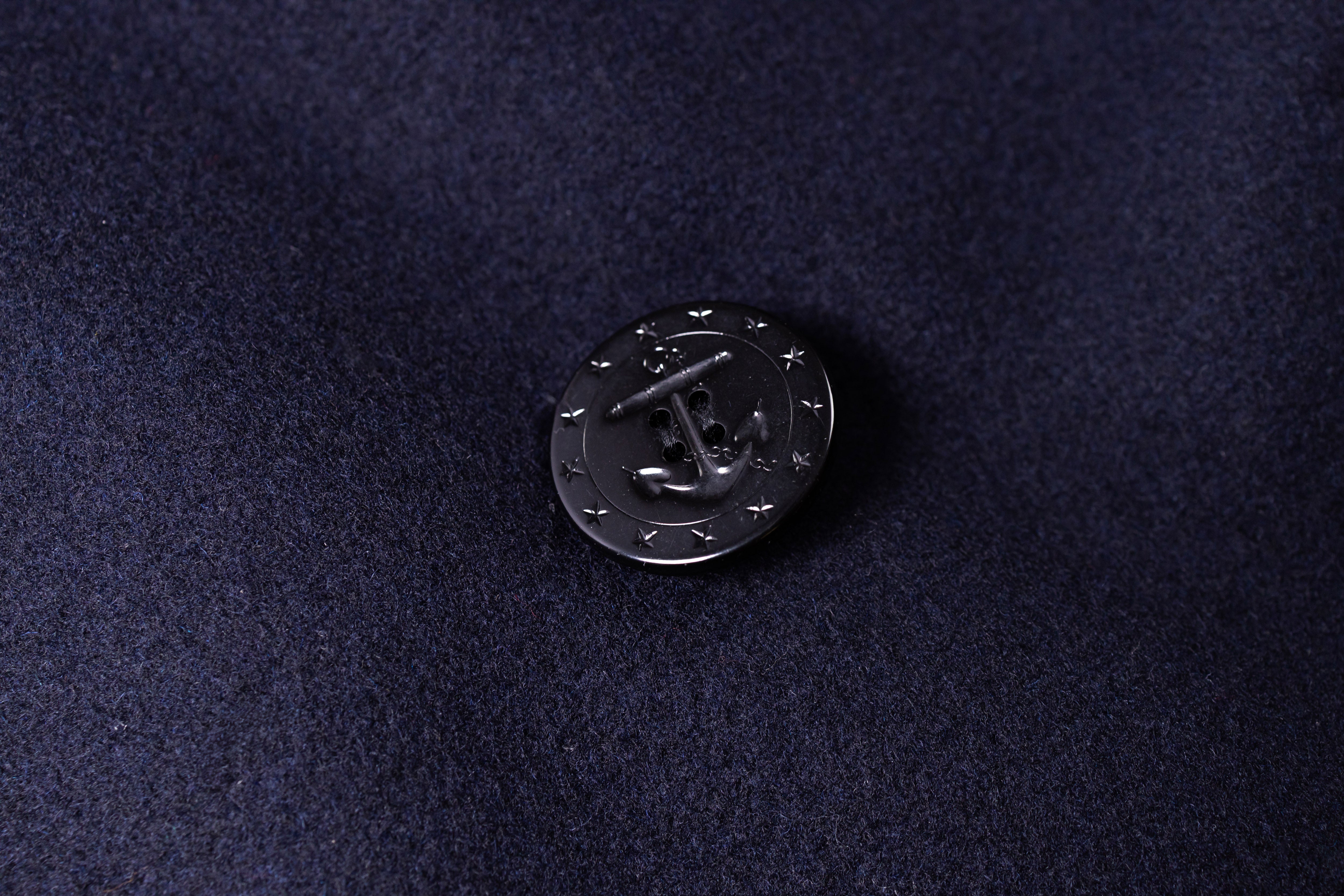 Black metal anchor pin on a dark blue fabric background