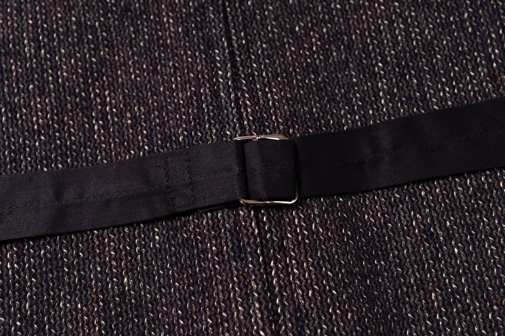 Close-up of a black belt with a buckle on a textured dark fabric background
