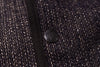 Close-up of a textured fabric with a button featuring a brand logo.