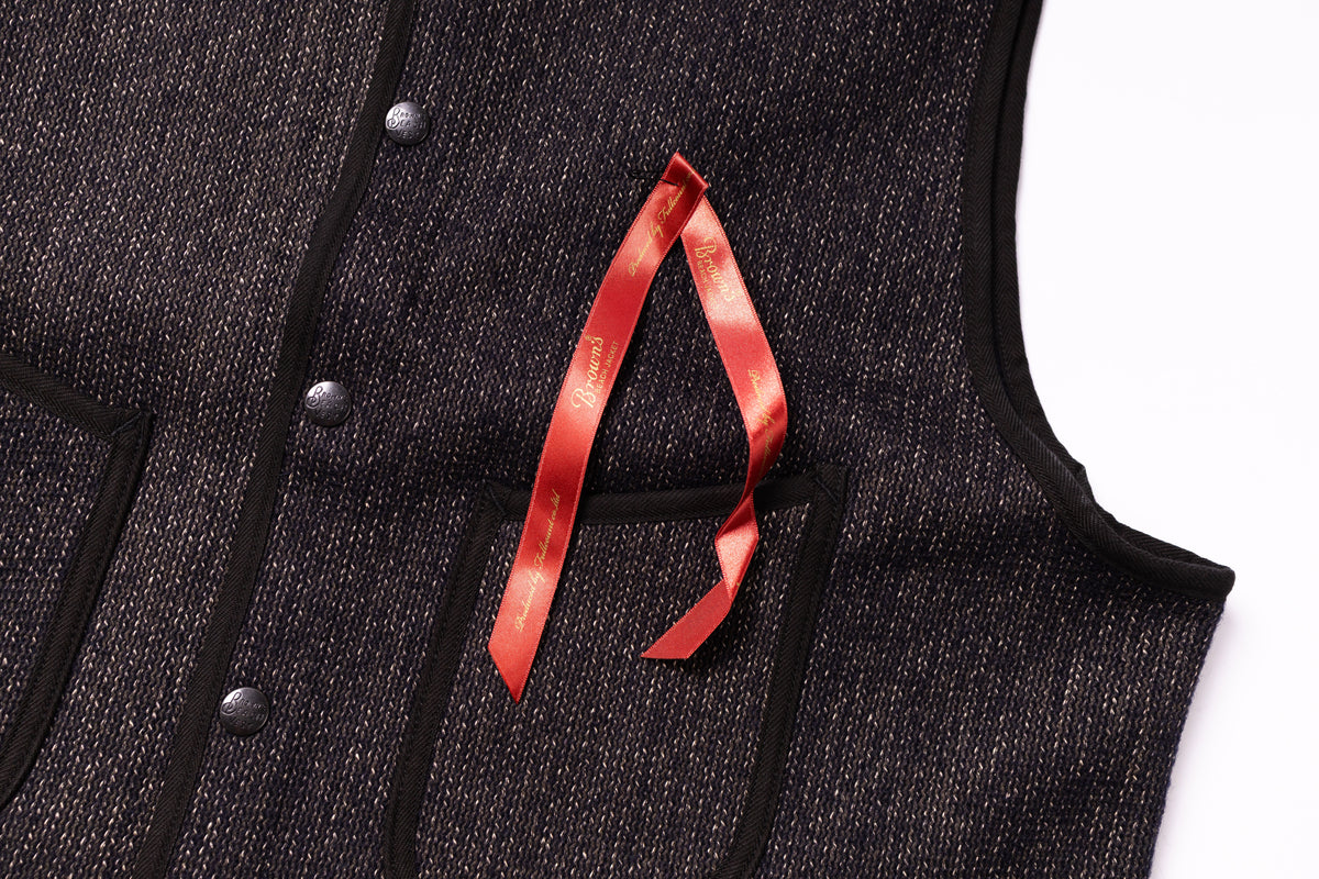 Black sleeveless jacket with a red ribbon detail on a white background