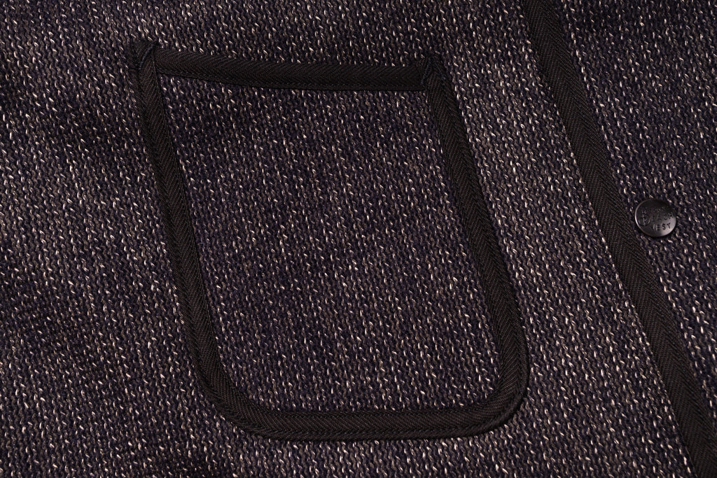 Close-up of a textured fabric pocket on a dark-colored garment.