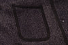 Close-up of a textured fabric pocket on a dark-colored garment.