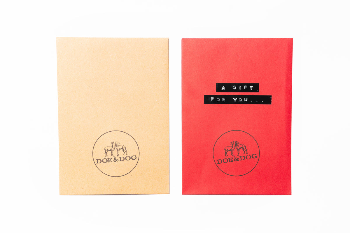 Two square gift envelopes or cards on a white background: one kraft beige with a black circular DOE&DOG logo, and one red with a black label reading 'A GIFT FOR YOU.