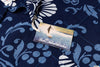 Close-up of a navy blue patterned shirt with a visible fabric tag wtih small surfing illustration on the tag.