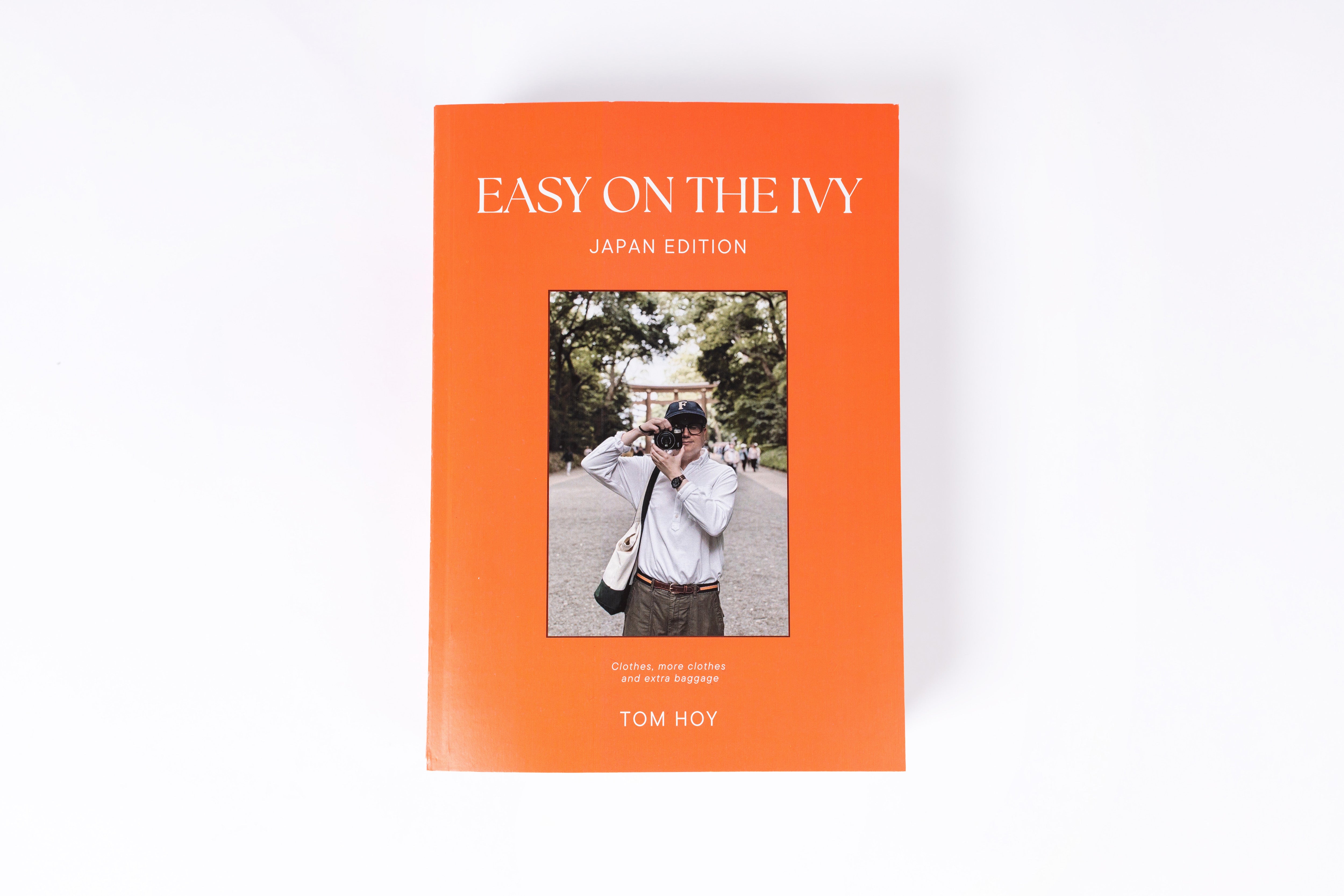 The front cover of the book 'Easy on the Ivy: Japan Edition' by Tom Hoy, featuring a bright orange background with white text and a central rectangular photograph of a person holding a camera, shown on a clean white background.