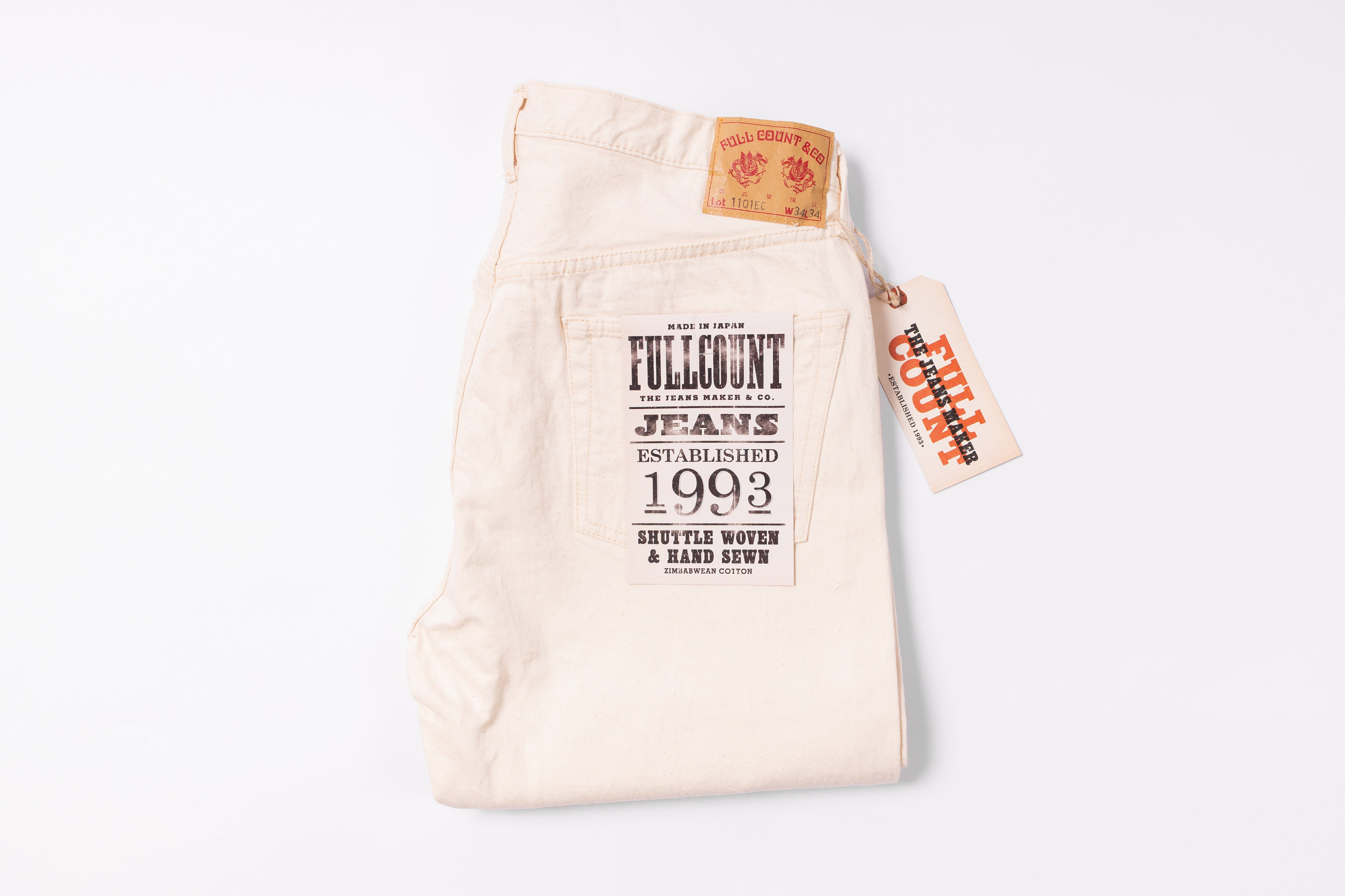 White jeans with a brand tag on a light gray background