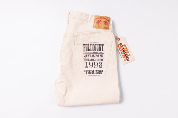 White jeans with a brand tag on a light gray background