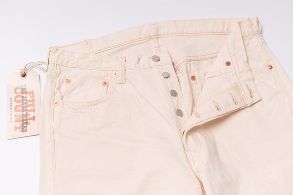 Beige jeans with a tag on a light gray background