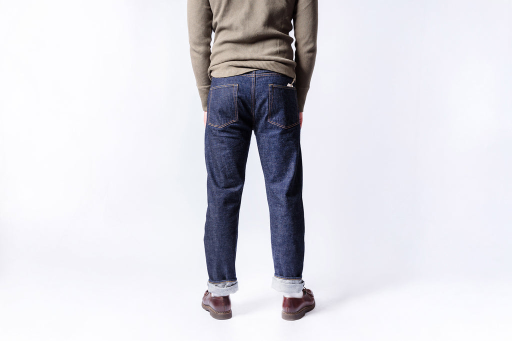 Person wearing blue jeans and a beige sweater on a white background