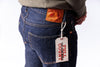 Person wearing blue jeans with a visible brand tag on a white background