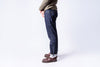 Person wearing dark blue jeans and brown shoes on a white background