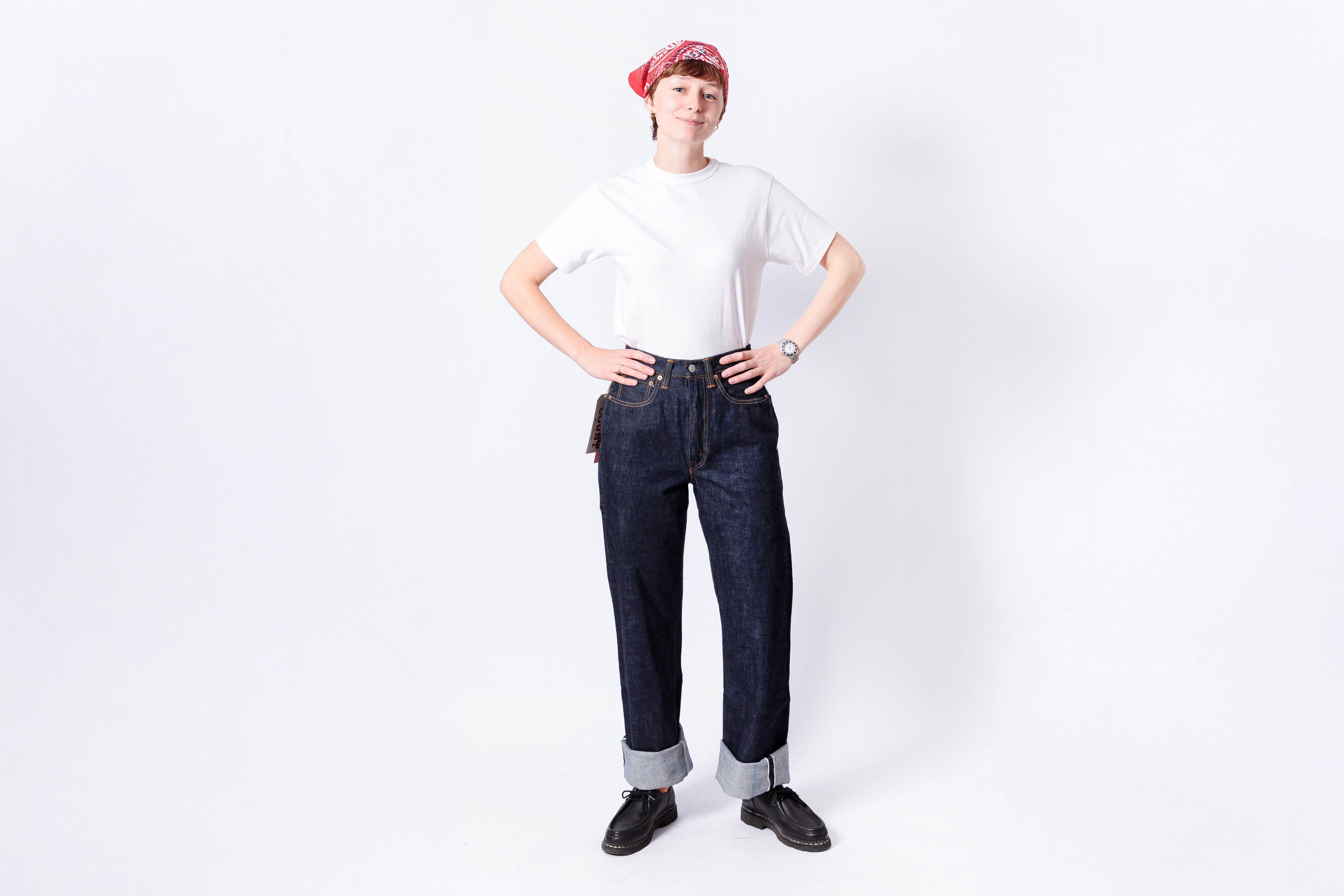 Person wearing a white t-shirt, dark jeans, and a red bandana on a white background
