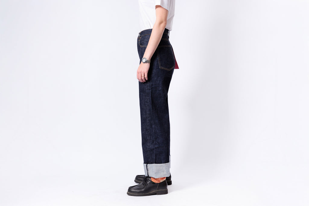 Person wearing dark blue jeans and black shoes on a white background