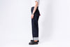 Person wearing dark blue jeans and black shoes on a white background