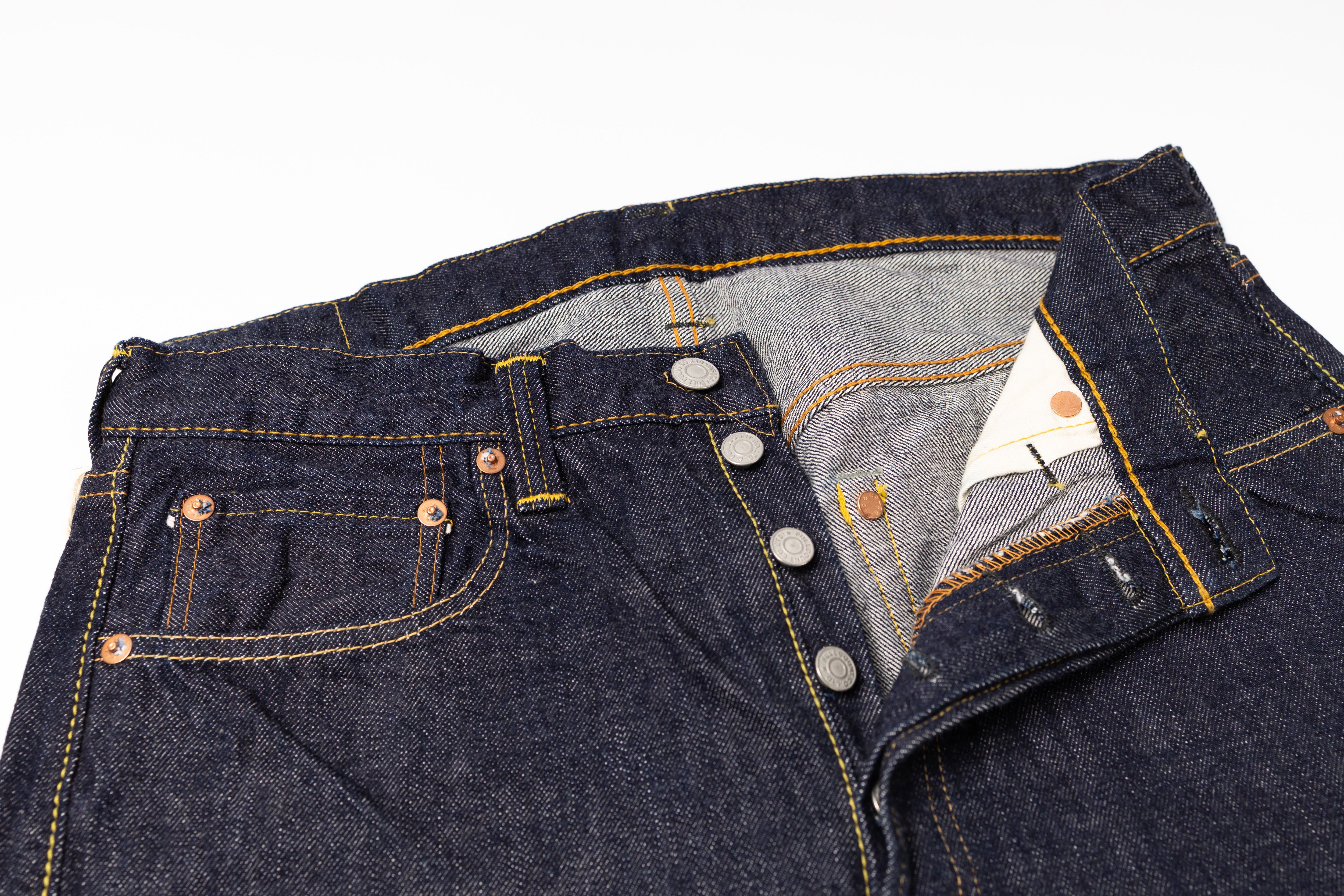 Close-up of a folded pair of dark blue jeans with a white background