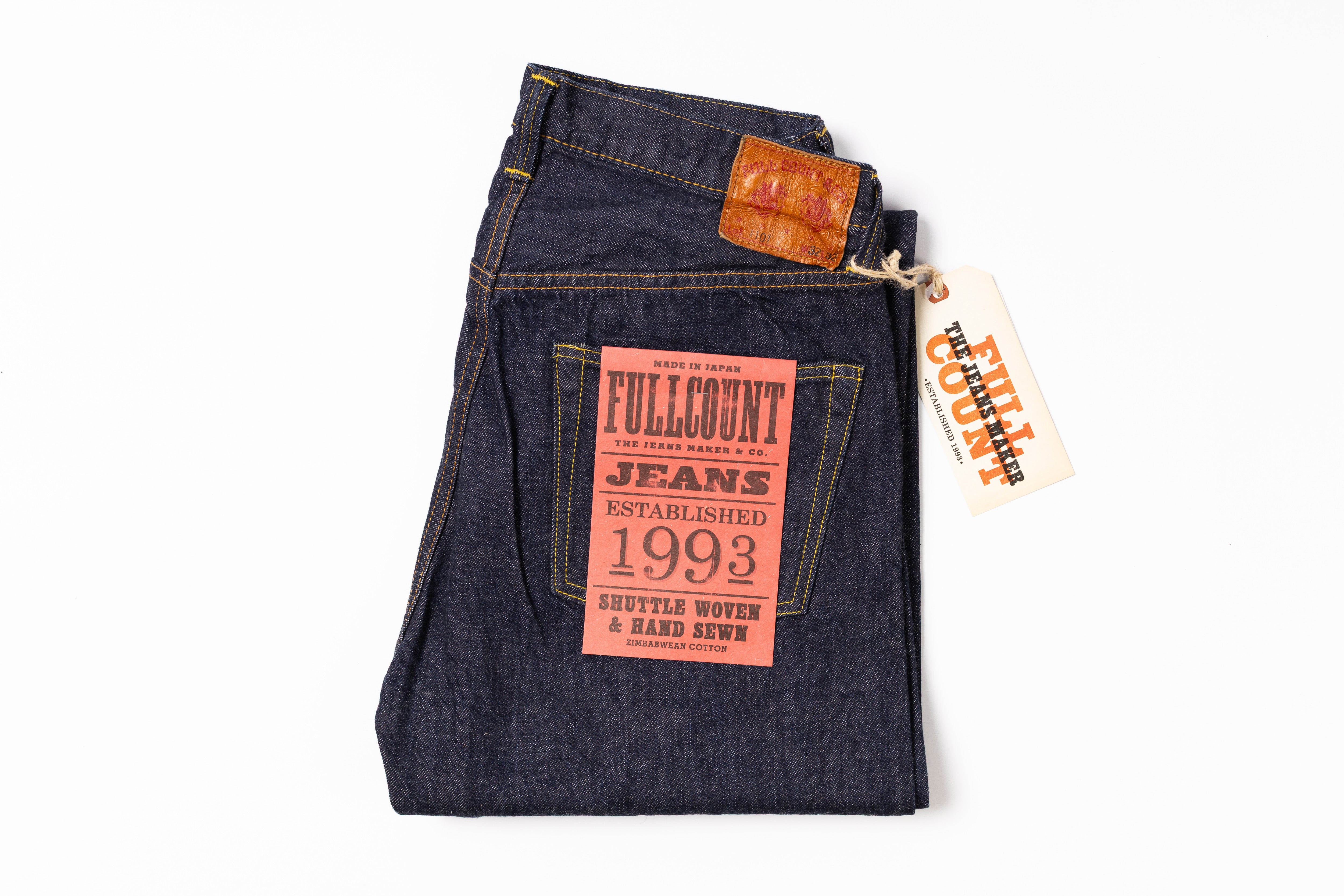 Folded pair of jeans with a brand tag on a white background