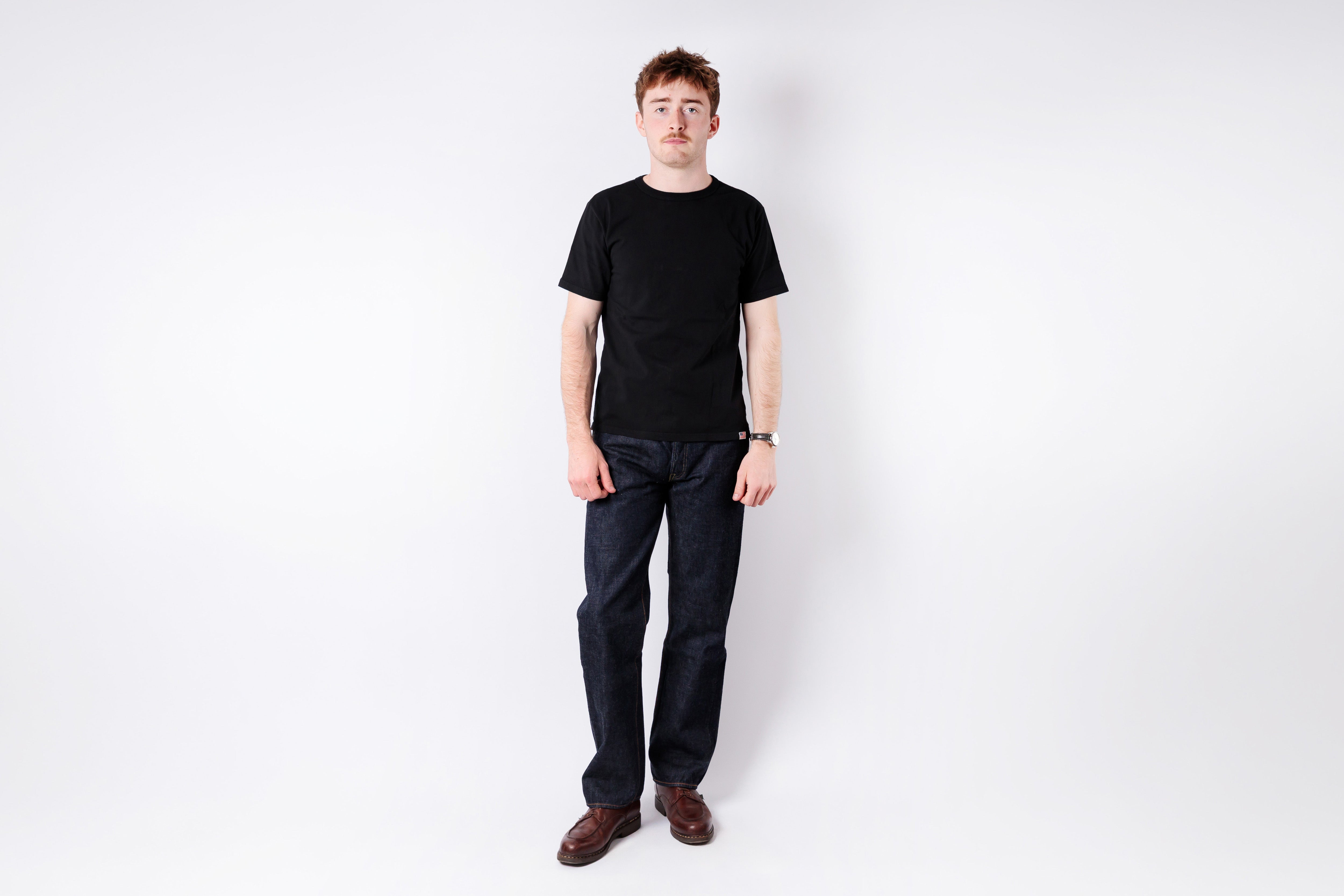 Person wearing a black t-shirt and dark pants on a white background
