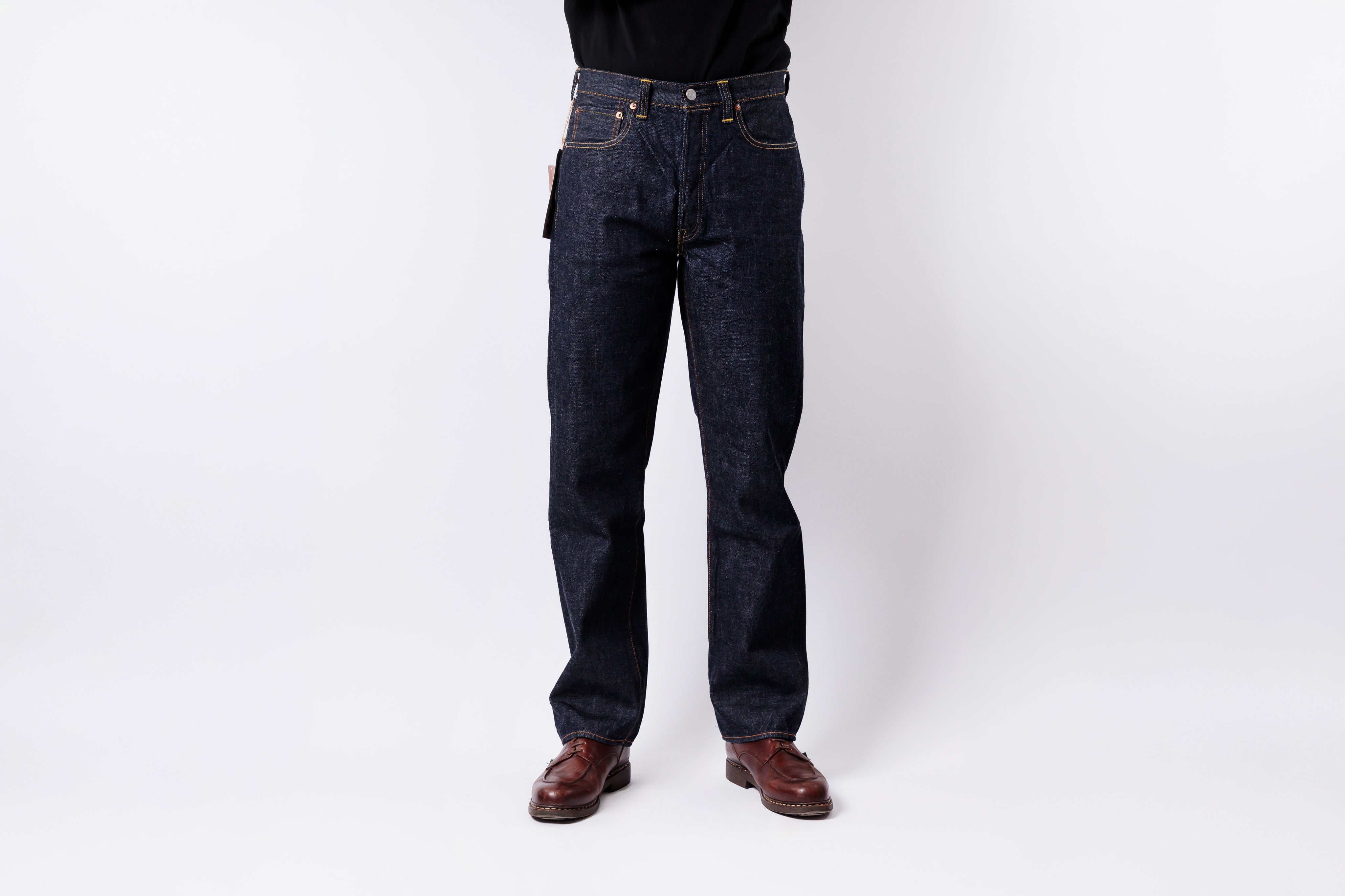 Person wearing dark blue jeans on a white background