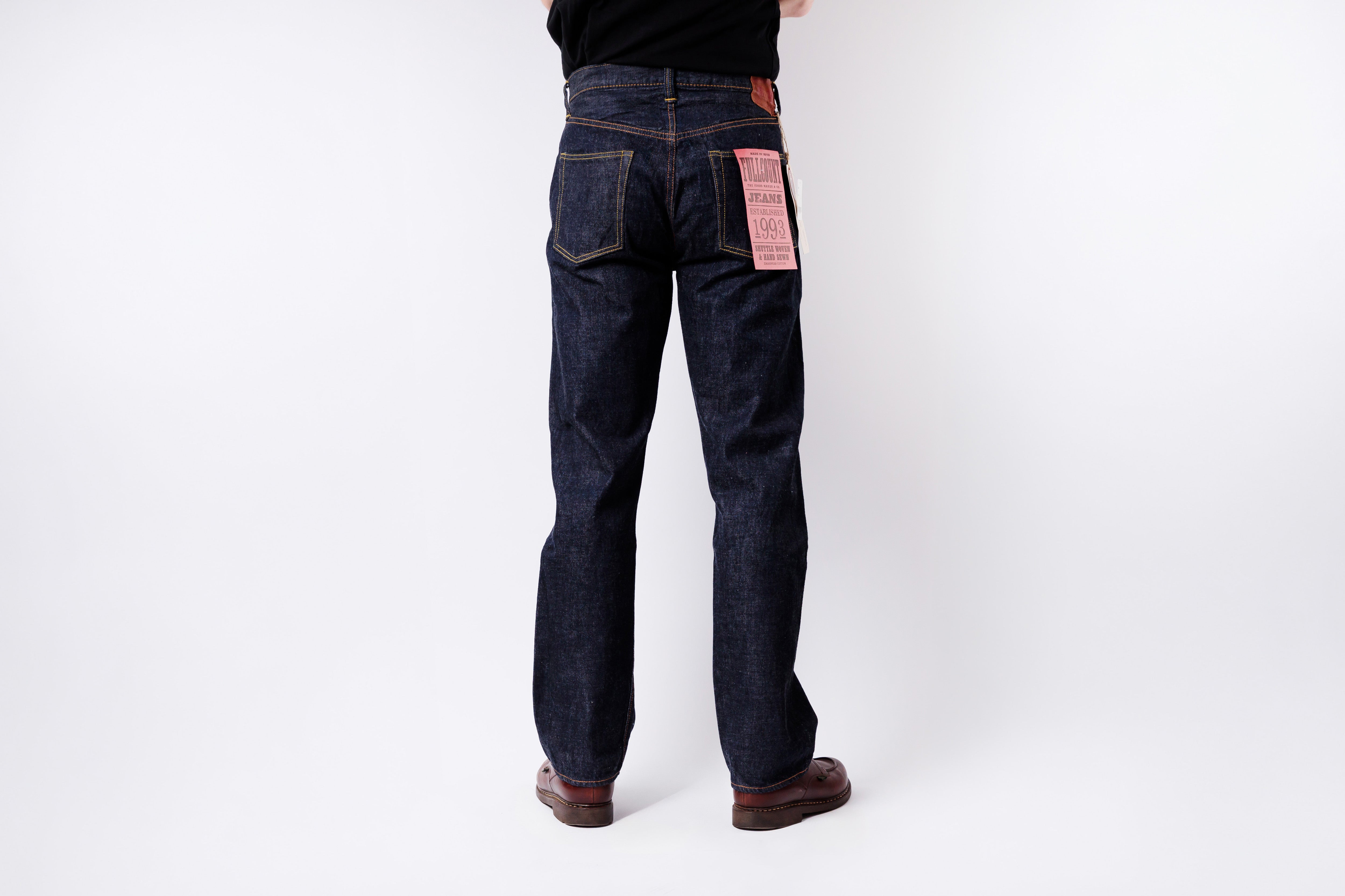 Person wearing dark blue jeans on a white background