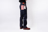 Person wearing dark blue jeans with tags on a white background