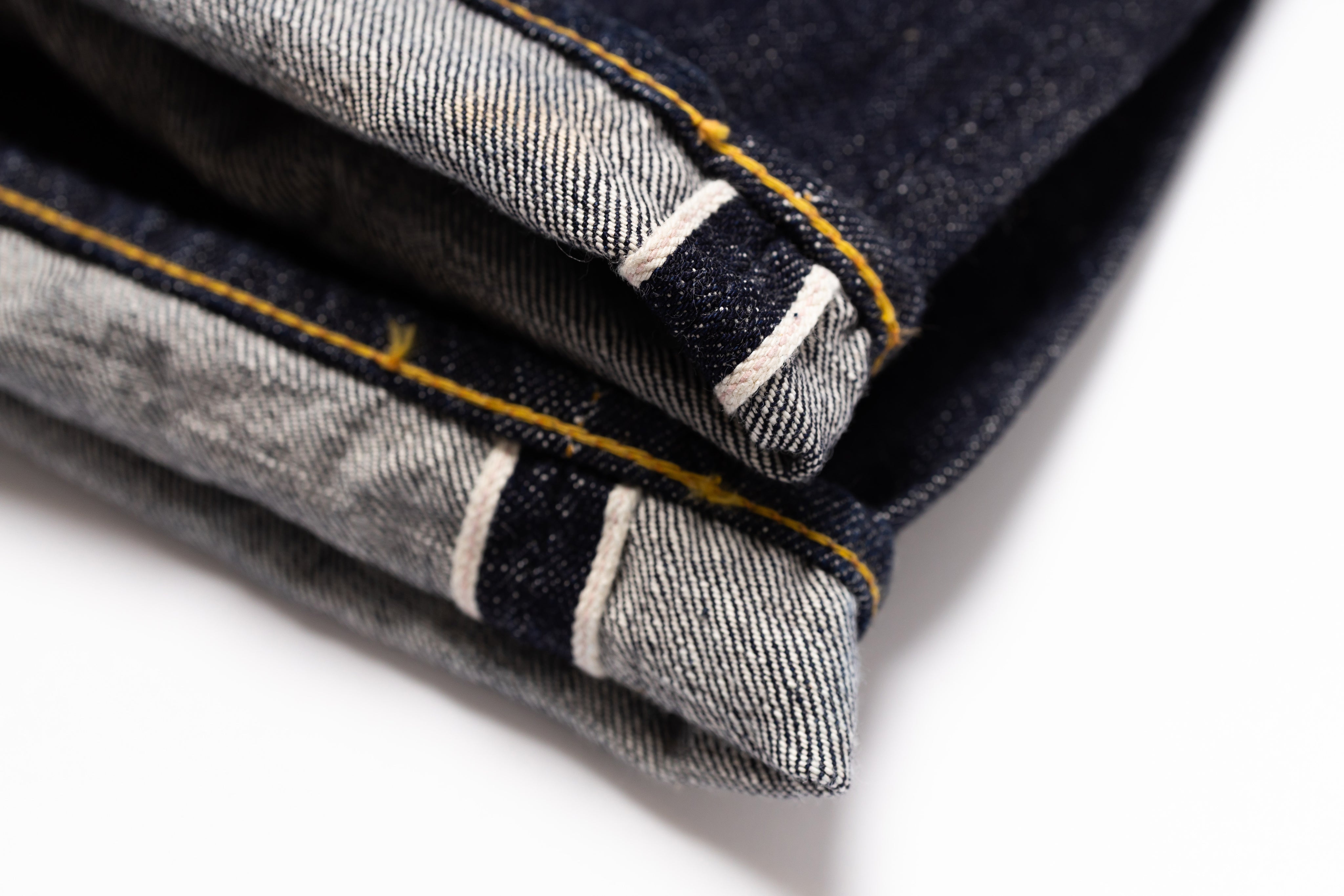 Close-up of folded denim jeans with visible stitching on a white background