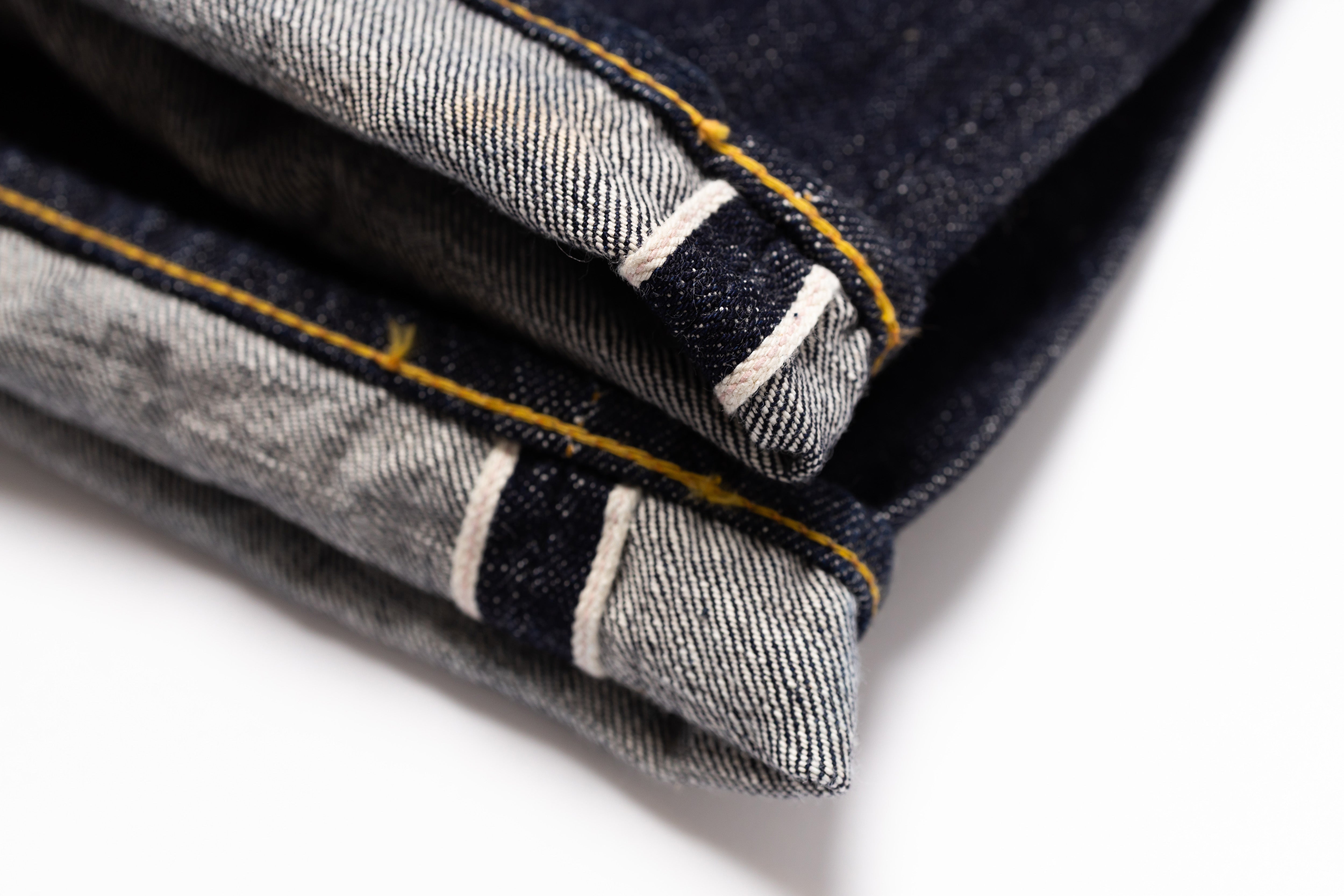 Close-up of folded denim jeans with visible stitching on a white background