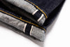 Close-up of folded denim jeans with visible stitching on a white background
