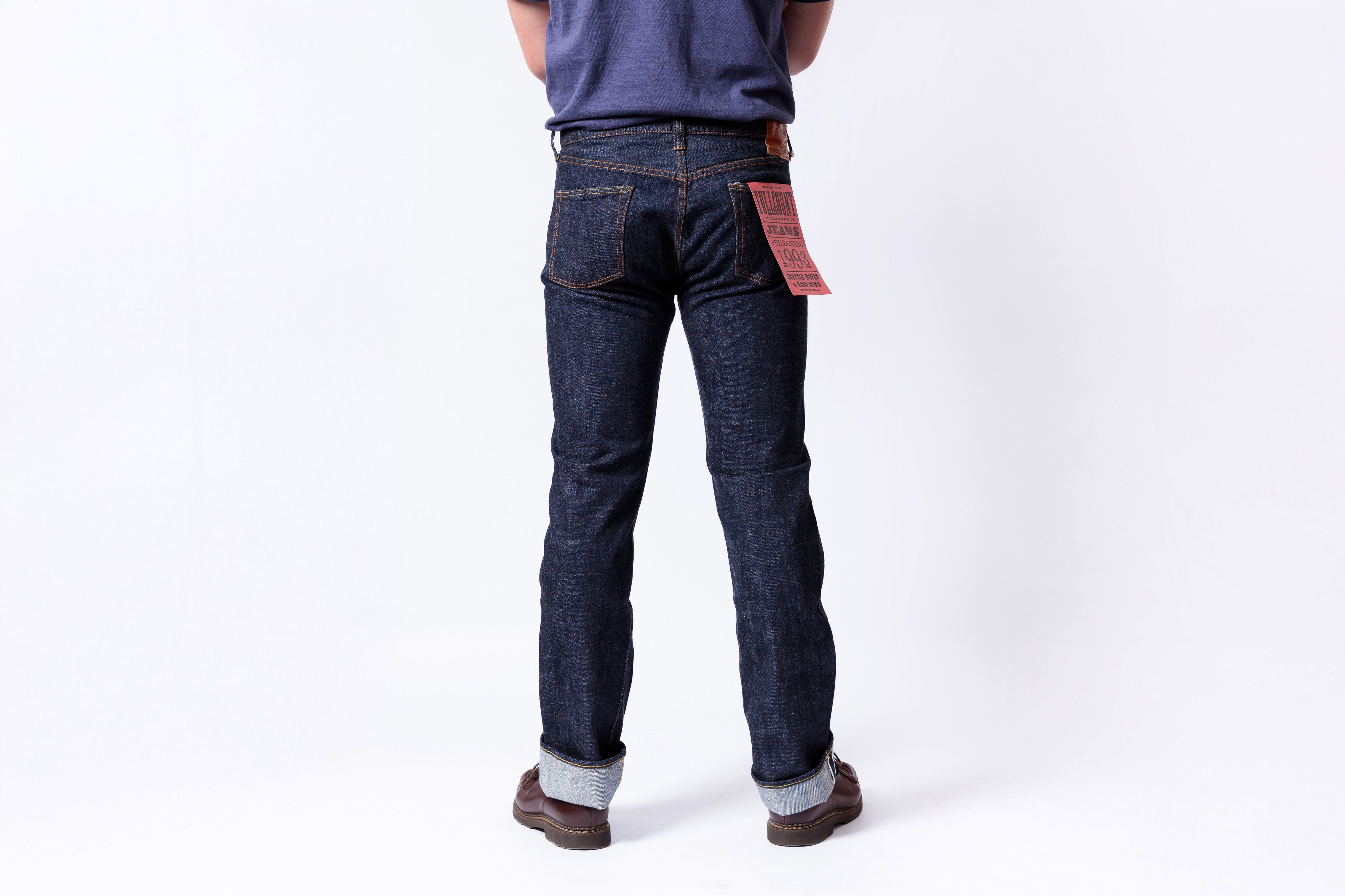 Person wearing dark blue jeans on a white background