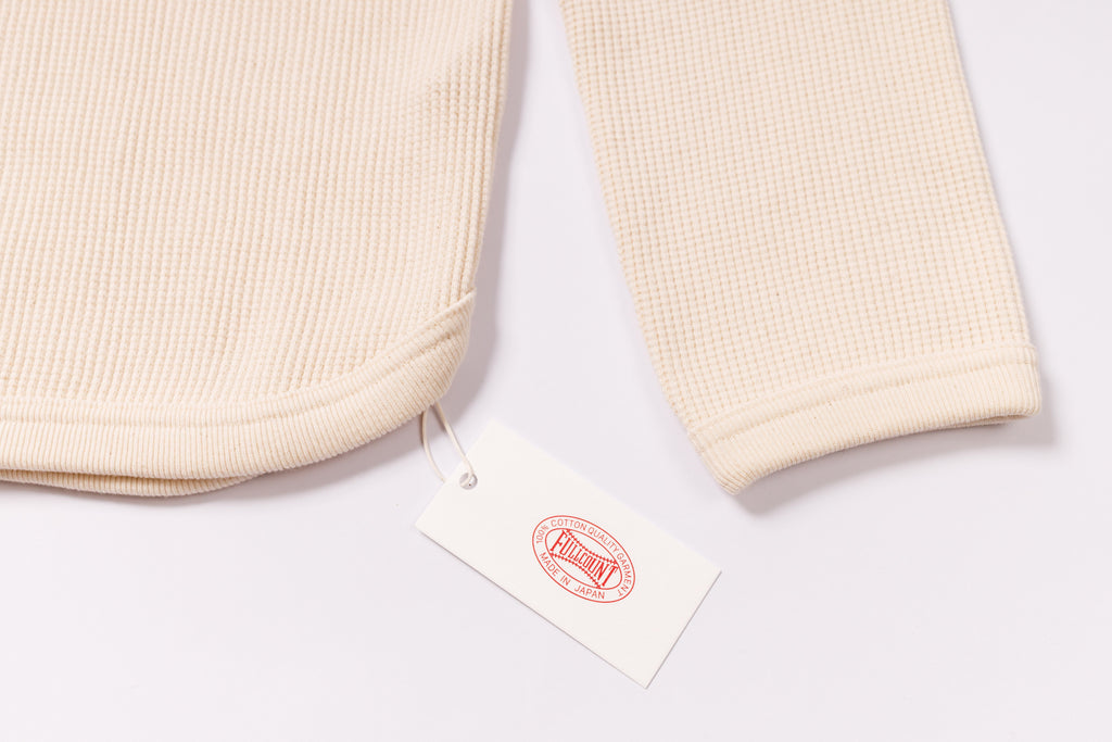 Beige textured fabric with a brand tag on a white background