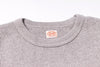 Close-up of a textured gray sweater with a brand label on a white background