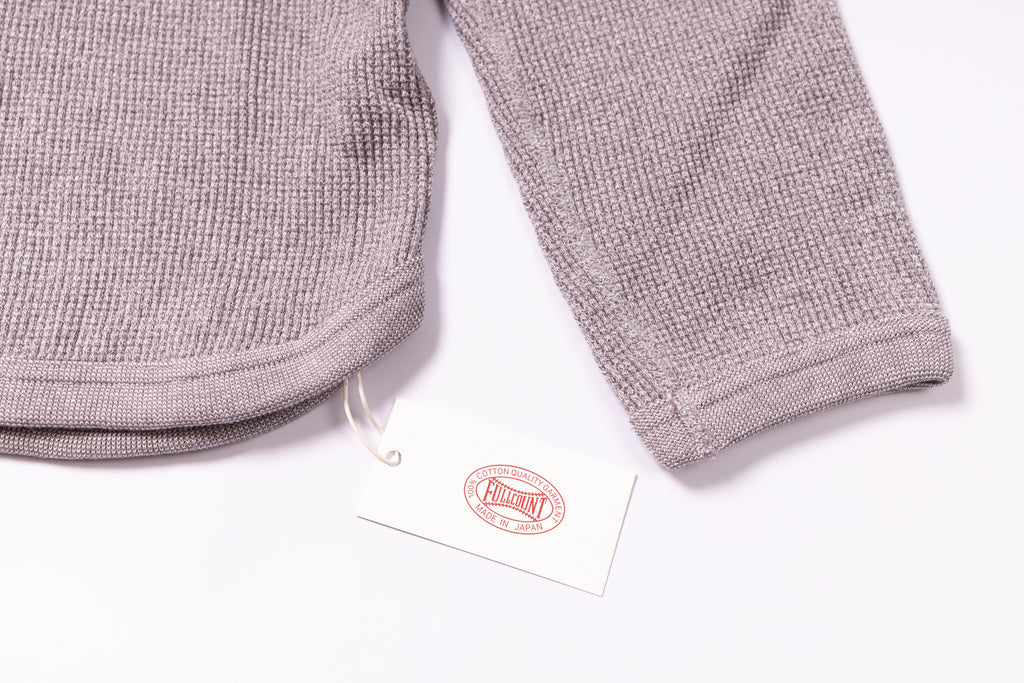 Gray textured pants with a tag on a white background