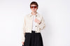 Person wearing a beige jacket and black skirt on a white background