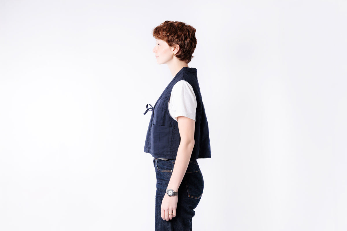 Person wearing a blue vest over a white shirt on a white background