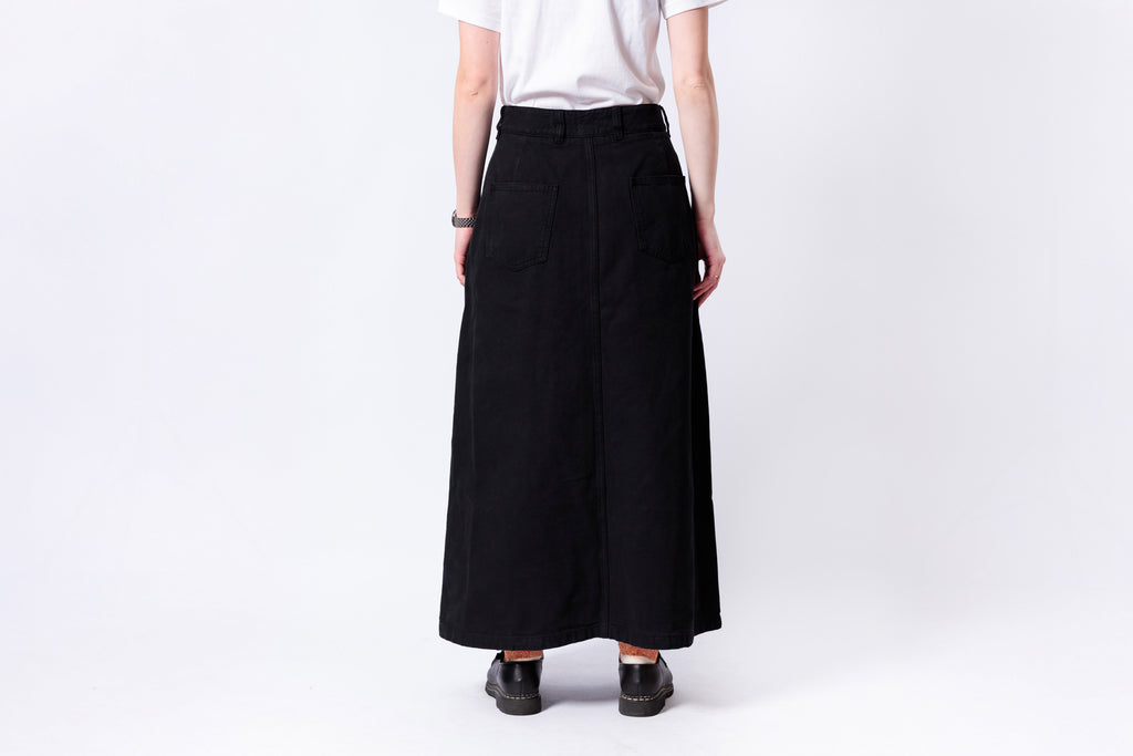 Person wearing a black skirt and white top on a plain background