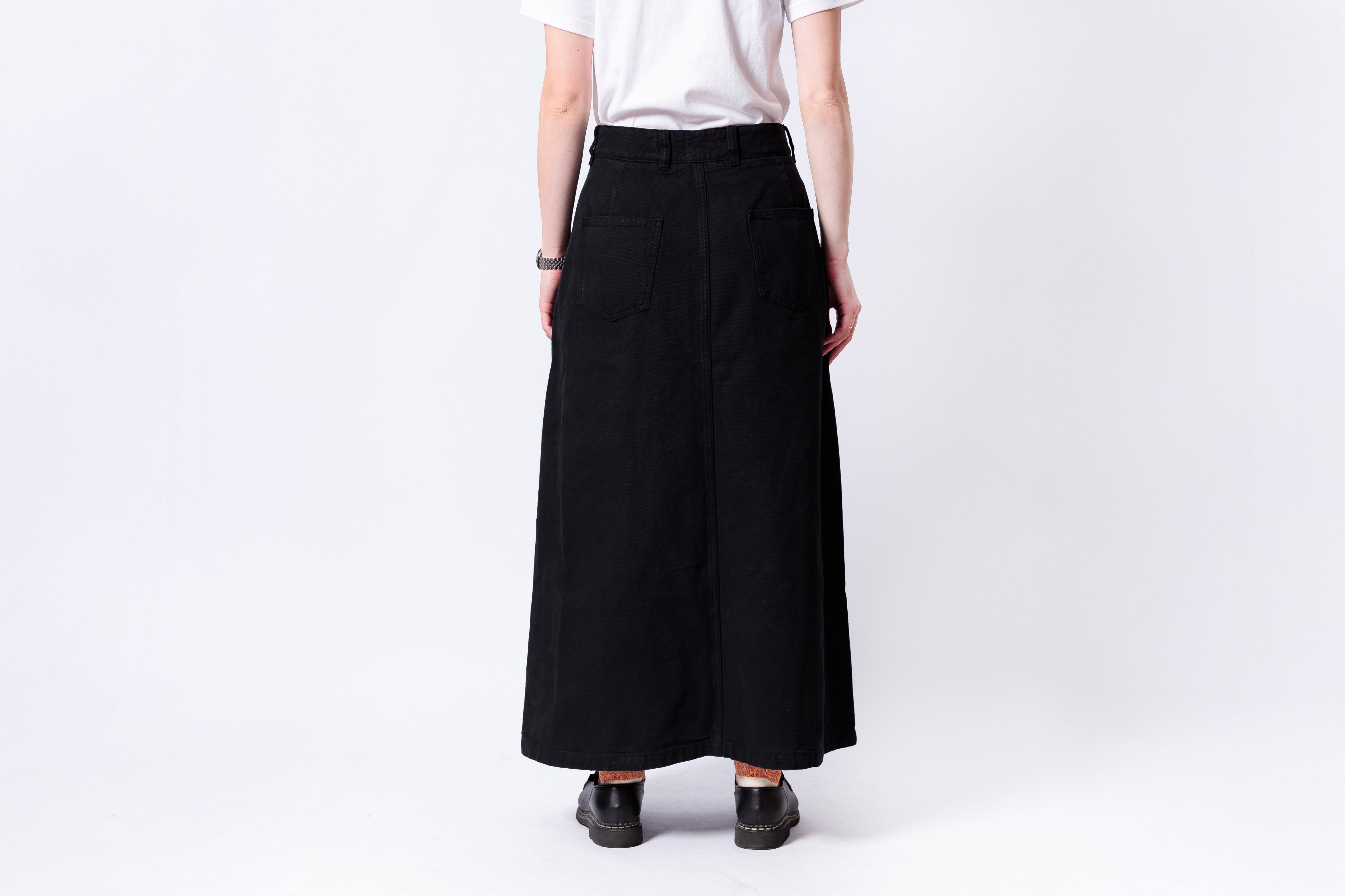 Person wearing a black skirt and white top on a plain background