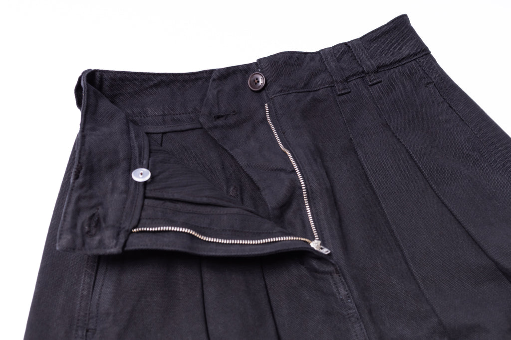 Close-up of black pants with a zipper and button on a white background