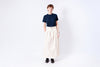 Person wearing a navy shirt and beige skirt on a white background