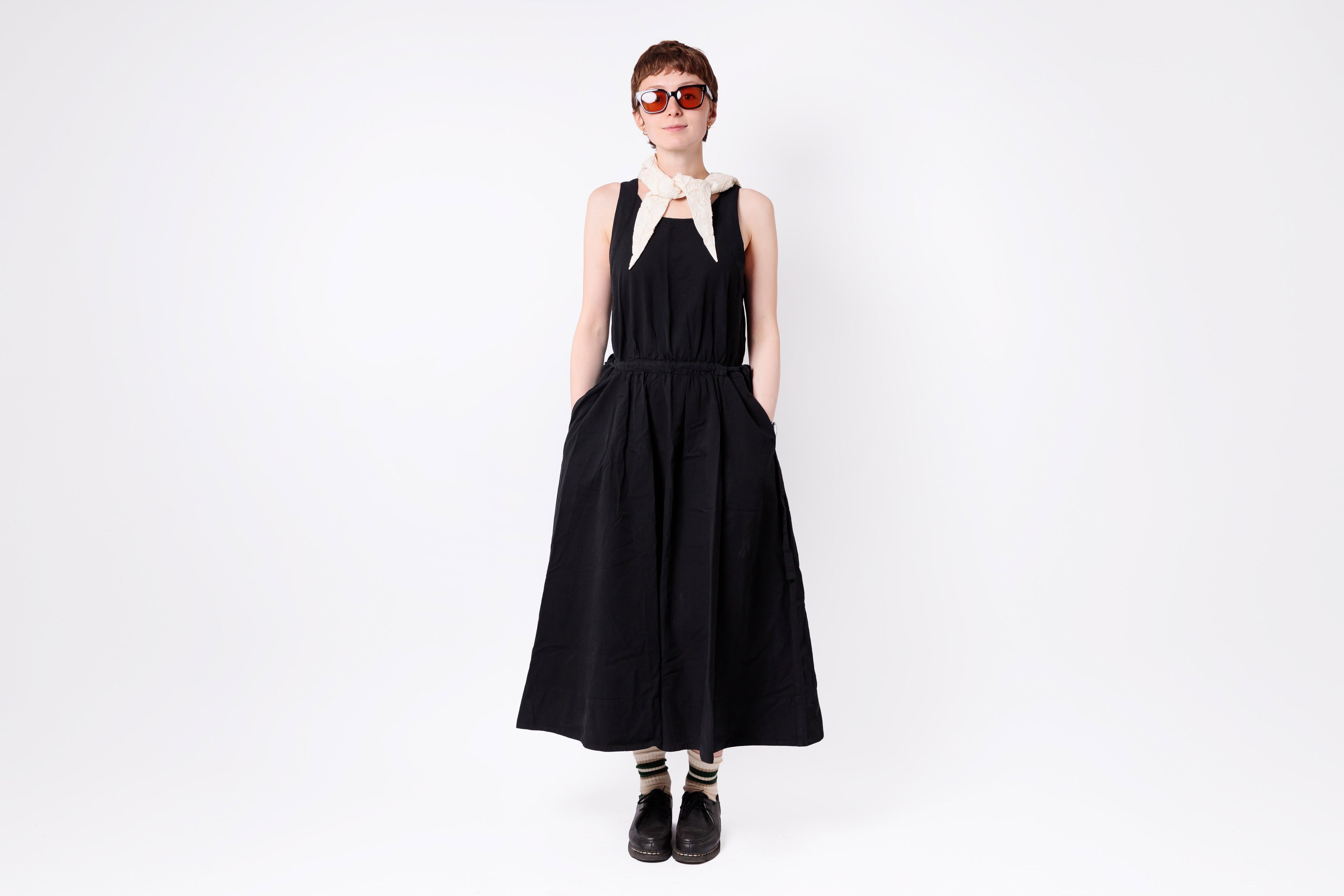 Person wearing a black dress with straps on a white background