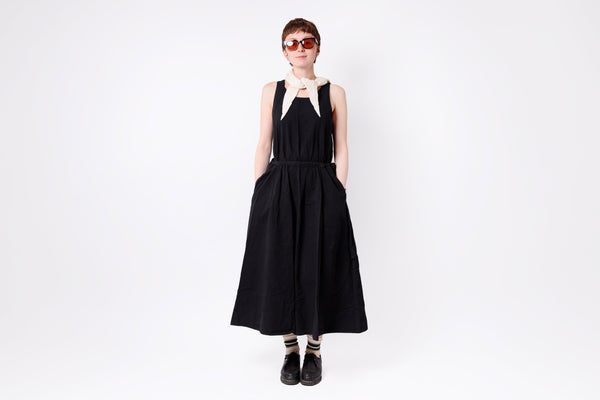 Person wearing a black dress with straps on a white background