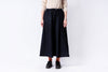 Person wearing a black skirt and beige sweater on a white background