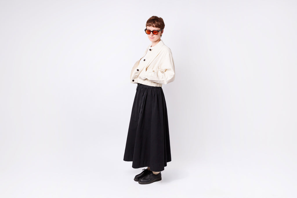 Person wearing a white jacket and black skirt on a white background